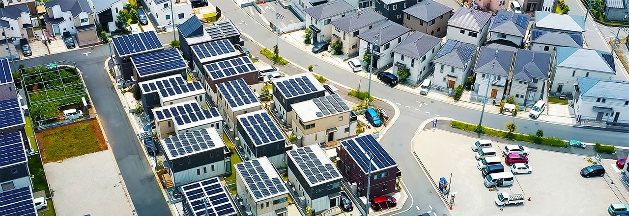 Aerial view of a modern residential neighborhood with houses featuring solar panels on their rooftops.