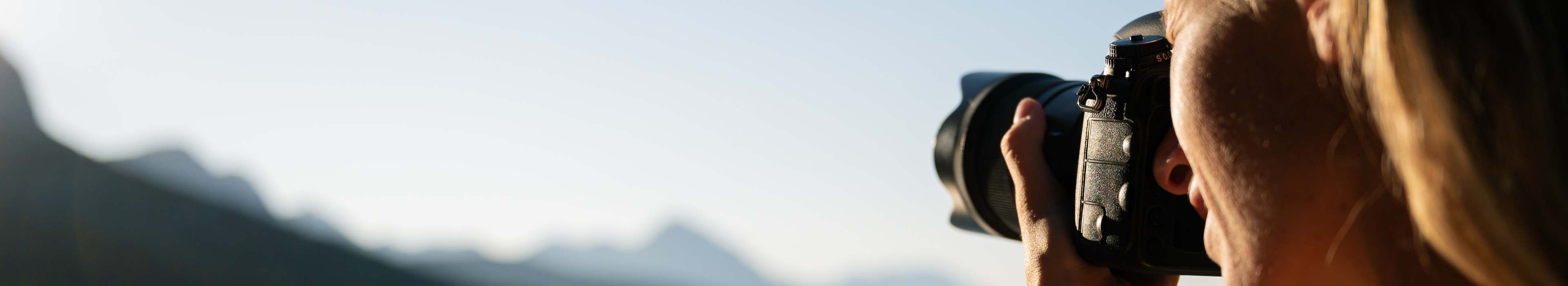Nahaufnahme einer Person, die ein Bergpanorama fotografiert.