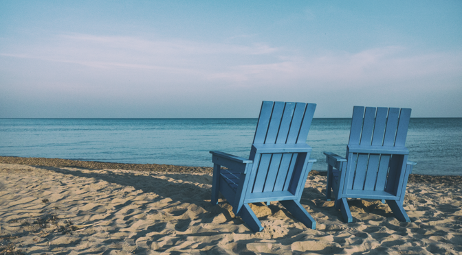 Zwei blaue Holzstühle am Strand