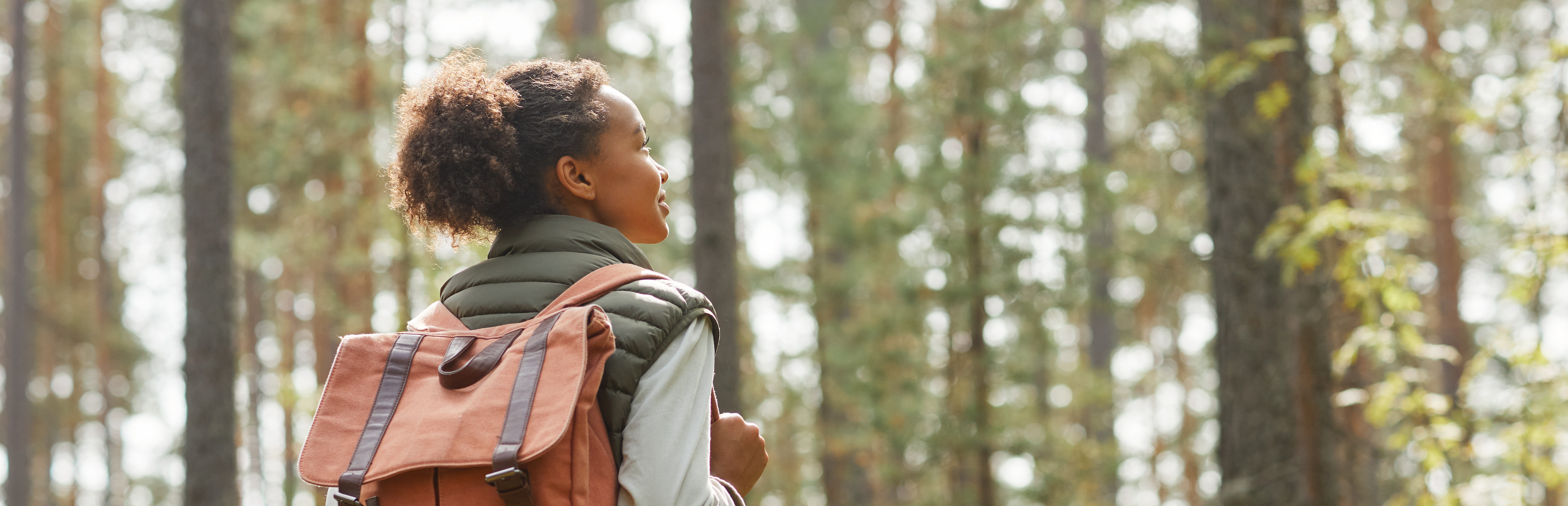 Eine junge Frau wandert draußen im Wald.