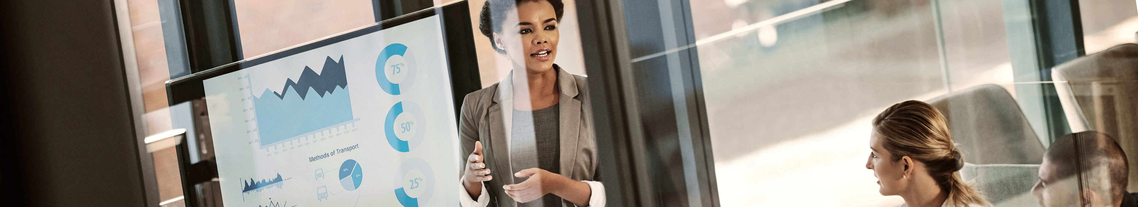 Eine Person präsentiert Finanzdaten und Statistiken auf einem Bildschirm während andere Personen zuschauen, ideal für innovative Finanzmarktforschung.