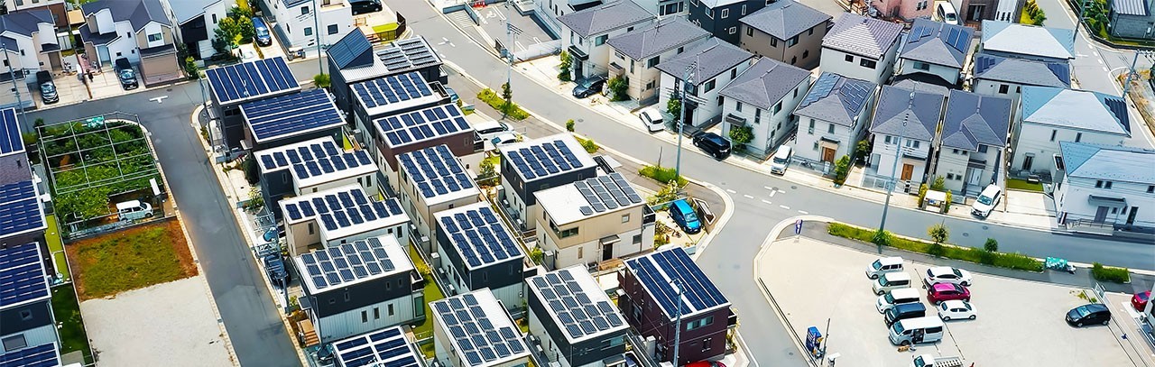 Moderne Wohnsiedlung mit zahlreichen Häusern, deren Dächer mit Solarpanels ausgestattet sind.