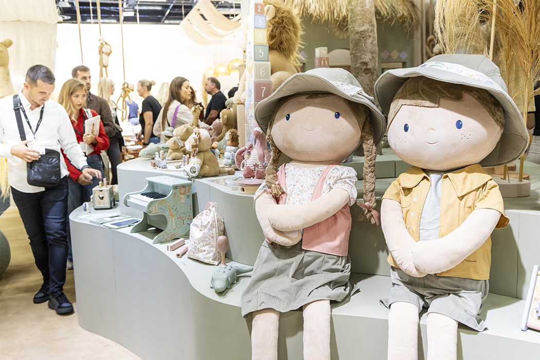 Menschen schauen sich Kinderspielzeuge an, unteranderem zwei große Puppen