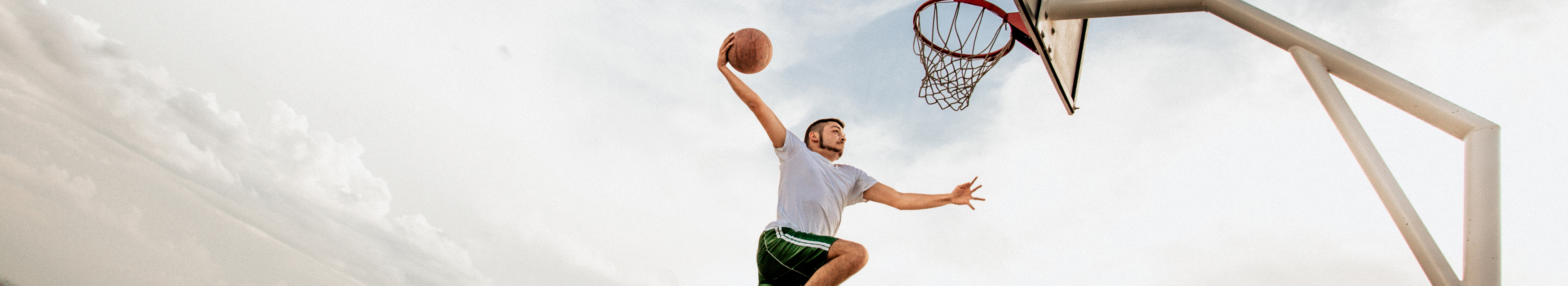 Person, die hochspringt und einen Basketball in den Korb wirft.