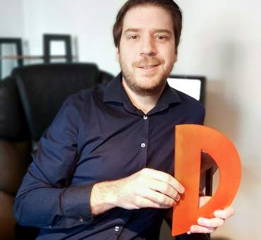 Person mit einem gebastelten Buchstaben D aus Pappe in den Händen.