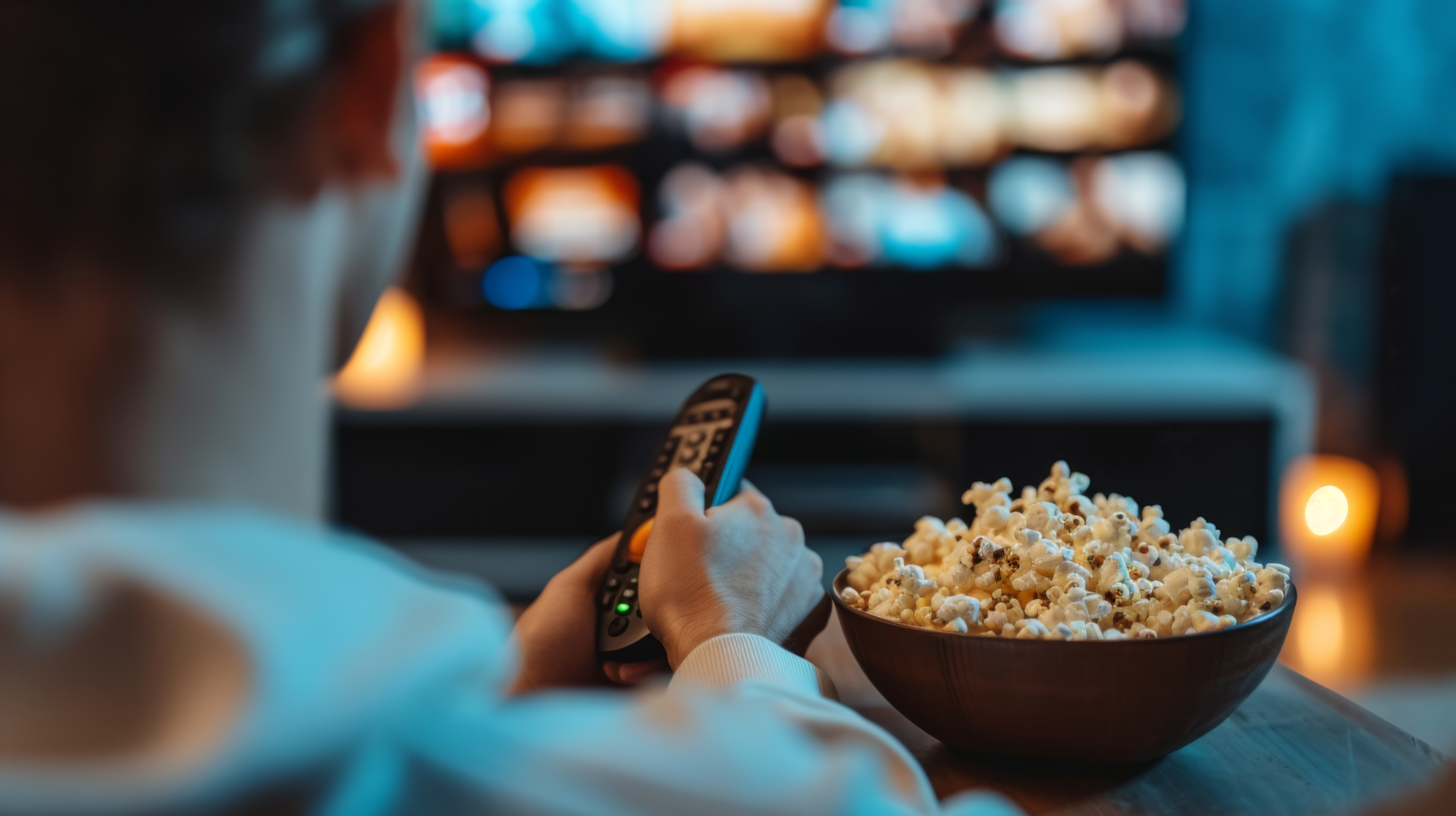 Junger Mann schaut Fernsehen und isst Popcorn 