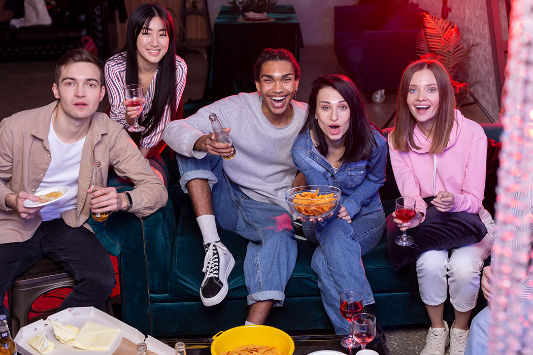 Gruppe junger Menschen sitzt zusammen, snackt und genießt Getränke.