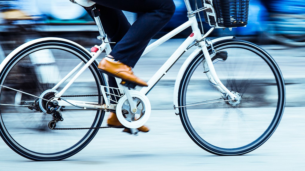 Bild des unteren Teils eines fahrenden Fahrrads mit verschwommenem Hintergrund.